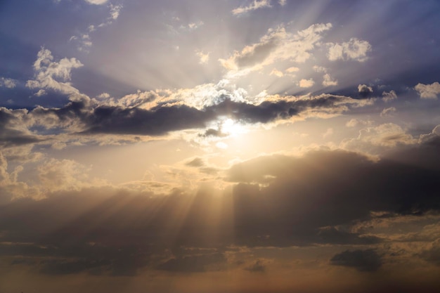 Empty cloudy sky from orange to blue with sun rays during the sunset