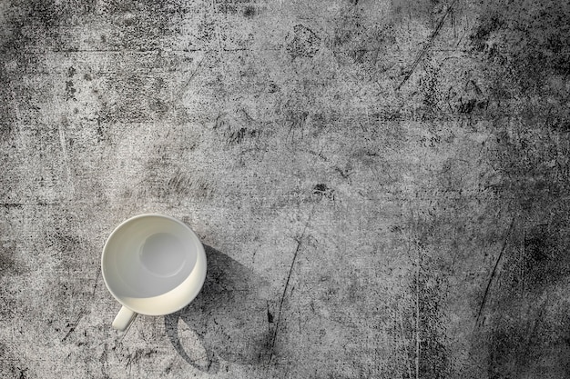 Empty coffee ceramic cup on concrete grunge style texture background and shimmering light Top view