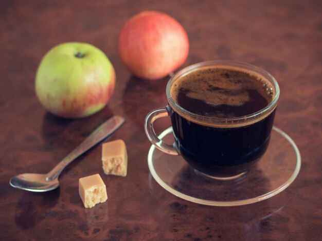 空のコーヒーカップスプーンとテーブルの上の2つのリンゴ。