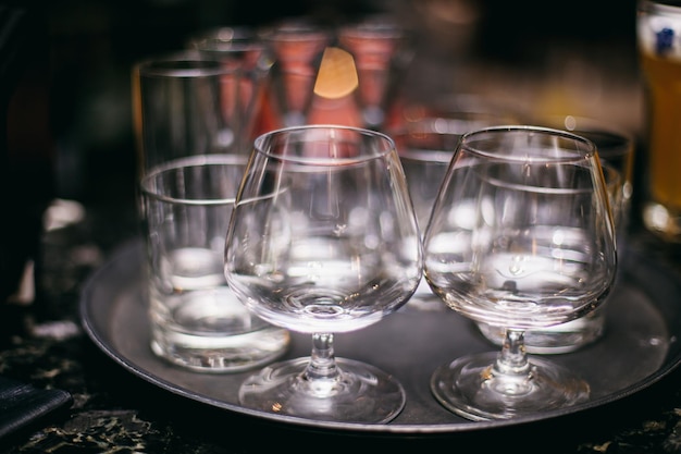 empty cognac glasses stand on a tray on the bar counter, dark background, close-up