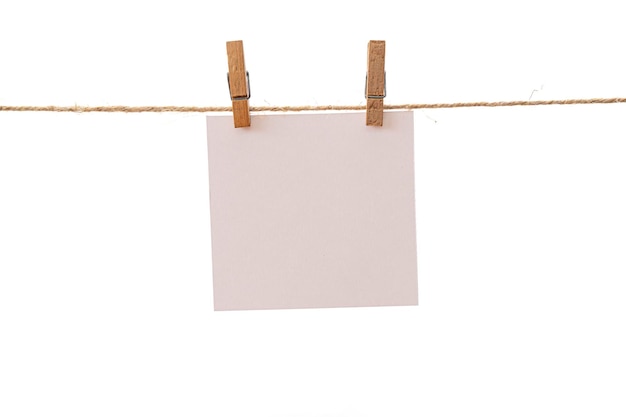 Empty color paper sheets for notes frames that hang on a rope with clothespins and isolated on white