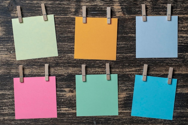 Empty colored paper sheets for notes with clothespins on wooden background Business concept copy space