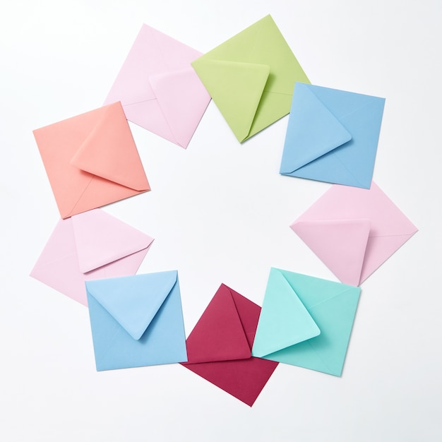 Empty colorful hndcraft envelopes in the shape of round frame on a light gray background with copy space.