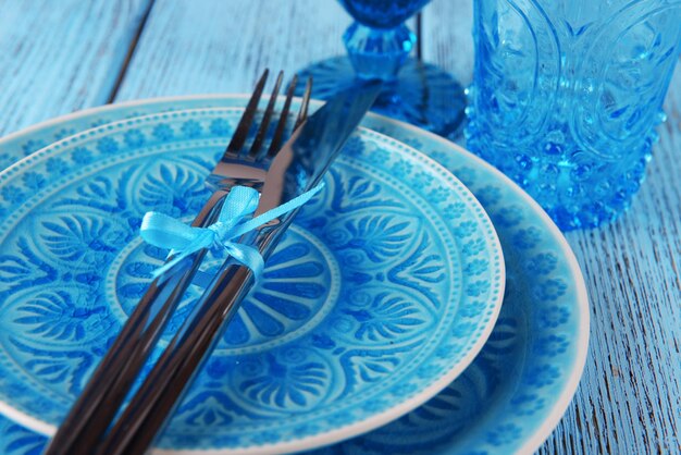 Empty colorful plate glasses and silverware set on wooden table