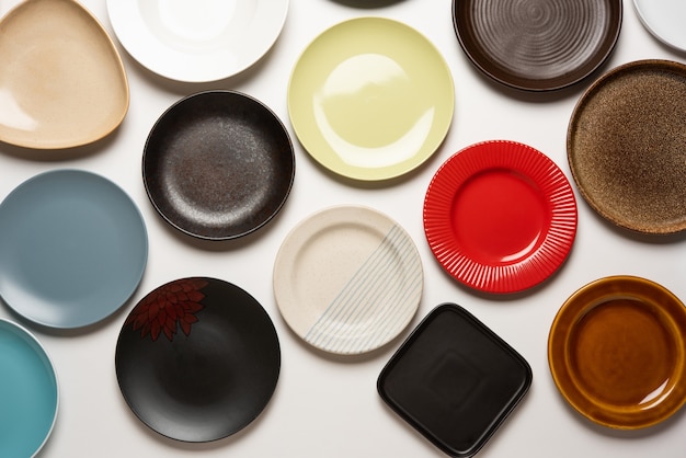 Empty colourful ceramic plates in group over white background, top view