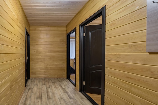 empty corridor in interior of entrance hall with many doors in wooden eco house or homestead