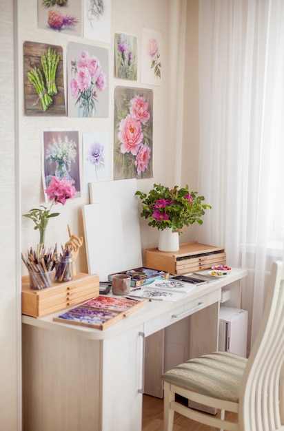 An empty cozy home workplace of the artist is place for hobby classes with bouquets of flowers and materials for creativity pencils and brushes. Inspiration concept