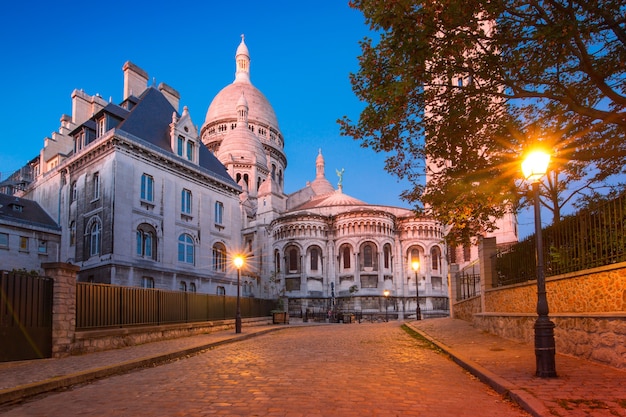 Empty cozy street and the Sacre-Coeur Basilica during morning blue hour, quarter Montmartre in Paris, France