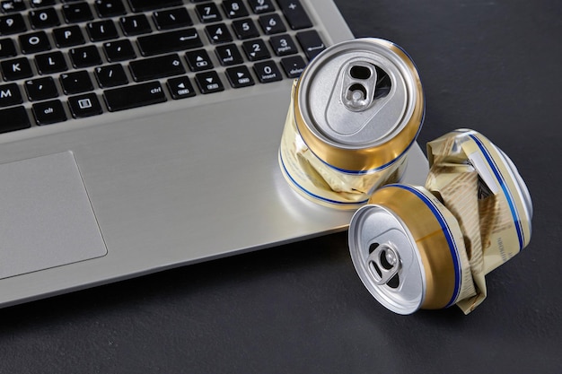 Photo empty crumpled beer cans on a laptop keyboard on a black backgro