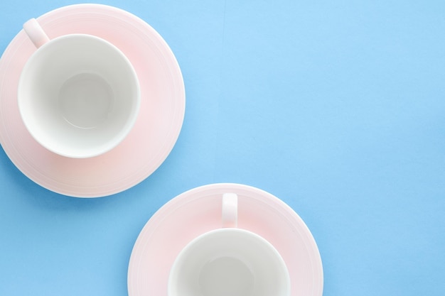 Empty cup and saucer on blue background flatlay