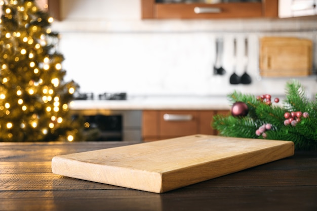 Empty cutting board on wooden tabletop with and blurred holiday kitchen