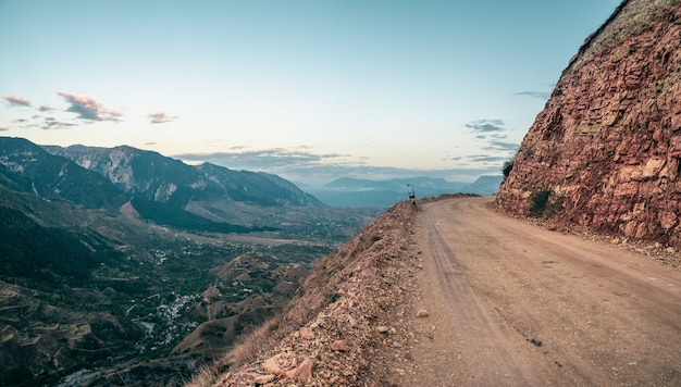 Empty dangerous narrow cliffside  mountain road. Dangerous off road driving along mountain edge and steep cliff. Dagestan.