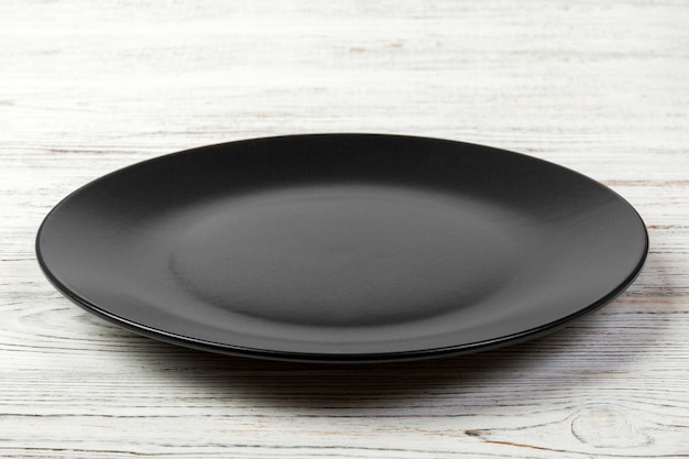 Empty dark matte dish for dinner on white wooden background