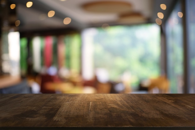 Photo empty dark wooden table in front of abstract blurred background of coffee shop . can be used for display or montage your products.mock up for display of product