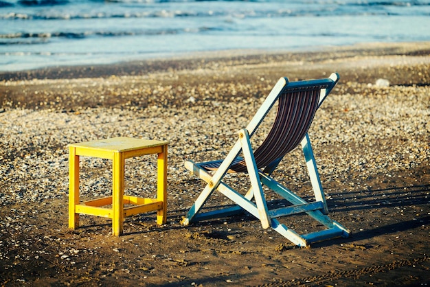 Foto sedie a sdraio vuote accanto a un tavolo sulla riva della spiaggia