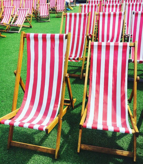 Empty deck chairs on grassy field at park