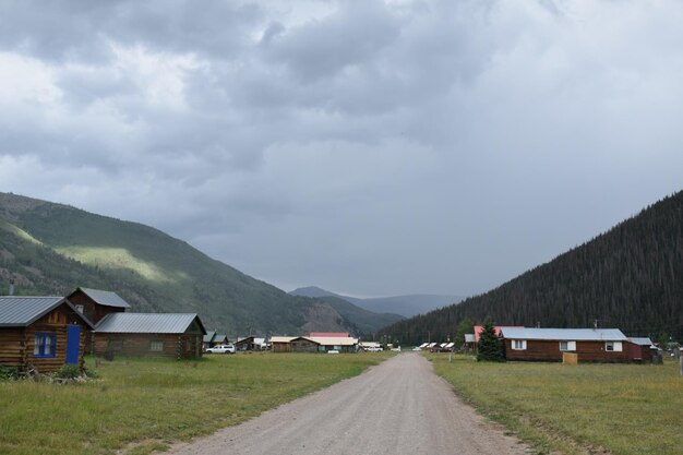 写真 雲の空に照らされた山へ向かう空っぽの土路