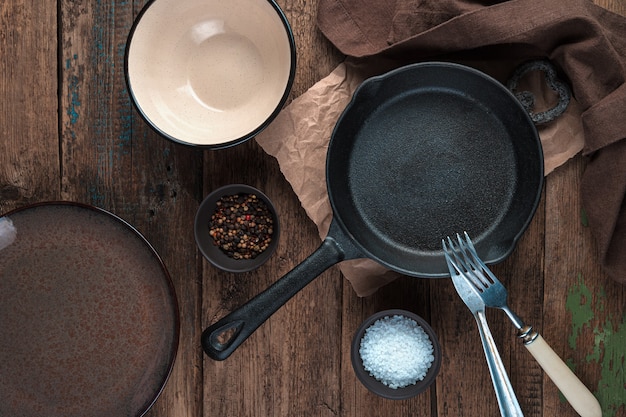 Photo empty dishes, frying pan, plates on a wooden background. the view from the top. concept for your design.