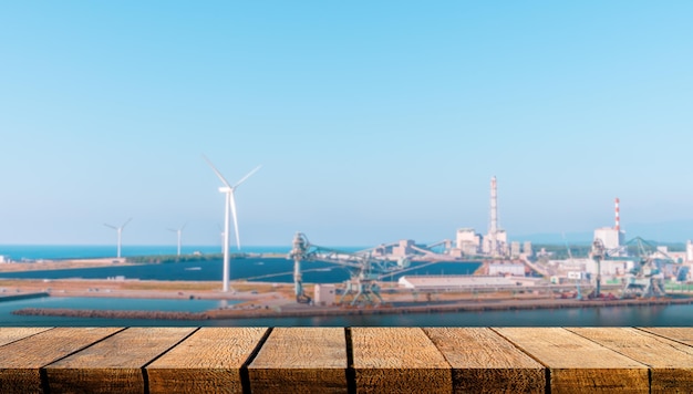 Foto tavola di legno vuota con spazio di copia per sfondo pubblicitario con sfondo di turbine eoliche nel settore delle energie rinnovabili