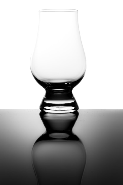 Foto bicchiere da degustazione di whisky dram vuoto e riflesso isolato su bianco