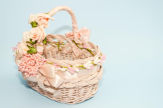 Empty easter basket decorated flowers and ribbon with blue background