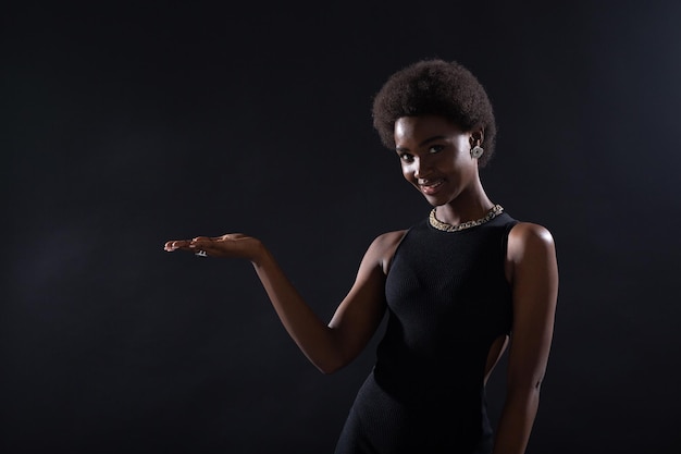 Mano femminile vuota della donna afroamericana che tiene su sfondo nero