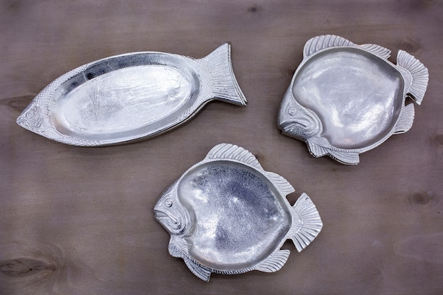 Empty fish-shaped silver plates on a wooden table