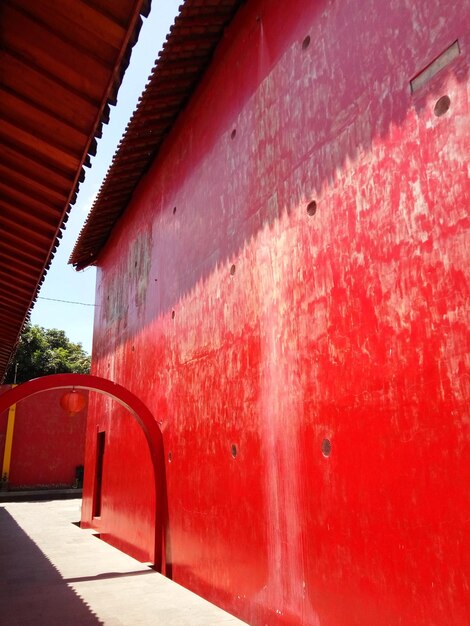 Empty footpath against red wall and building