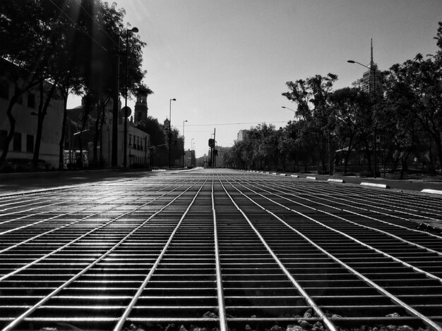 Empty footpath amidst buildings in city against sky