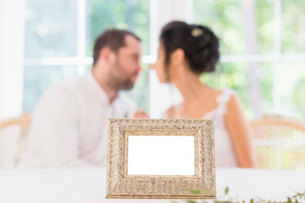 Empty frame on the background of the kissing bride and groom.