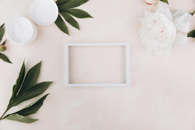 Empty frame and cream with peony flowers around