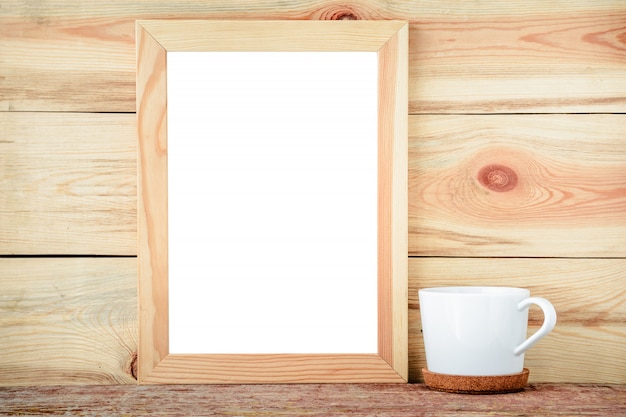 Empty frame and white cup on a wooden background.