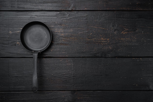 Empty frying pan set with copy space for text or food with copy space for text or food, top view flat lay, on black wooden table background