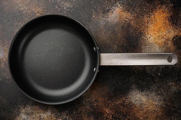 Empty frying pan set with copy space for text or food with copy space for text or food, top view flat lay, on old dark rustic table background