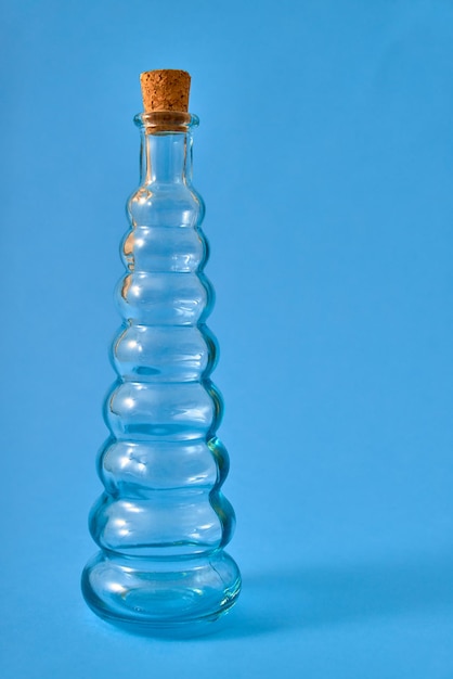 Empty glass bottle with original shapes on a solid neutral\
colored background.