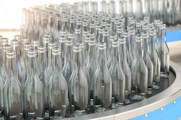 Пустые стеклянные бутылки на конвейерной ленте на заводе или в стекловладельческом предприятии