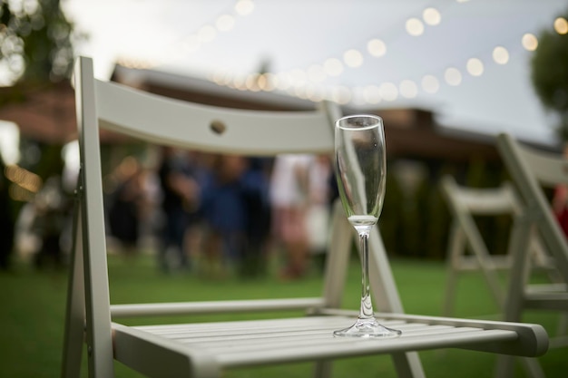 an empty glass of champagne stands on a white wooden chair