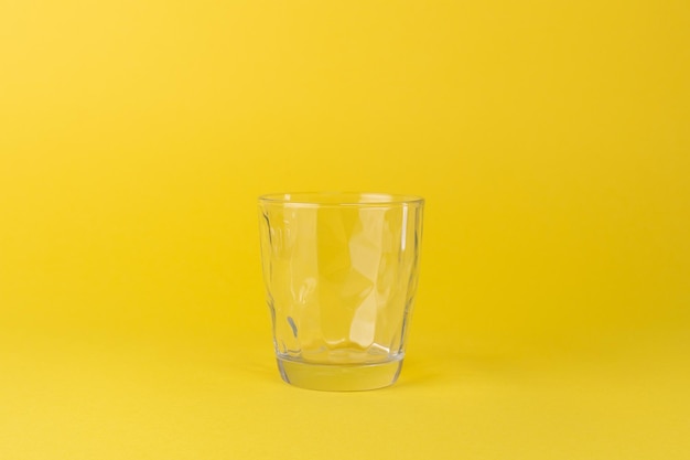 Empty glass cup on a yellow background