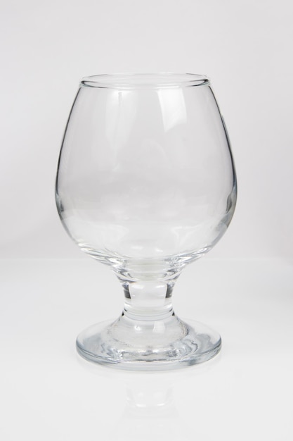 Пустой стеклянный бокал для коньяка на белом фоне
