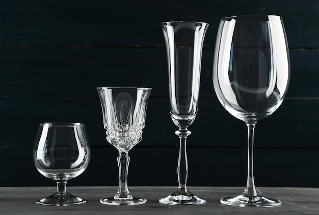 Empty glass goblets on dark color wooden background