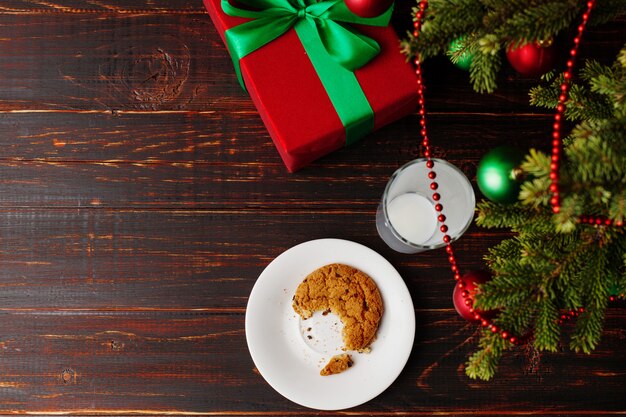 Empty glass of milk and crumb biscuits and a gift under the Christmas tree. The  of the arrival of Santa Claus.