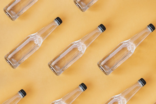 Empty glass water bottles on orange background