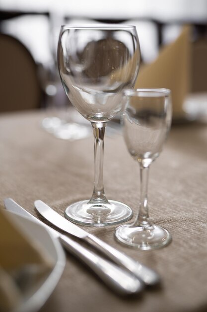 На праздничный стол подают пустые бокалы и другие столовые приборы.