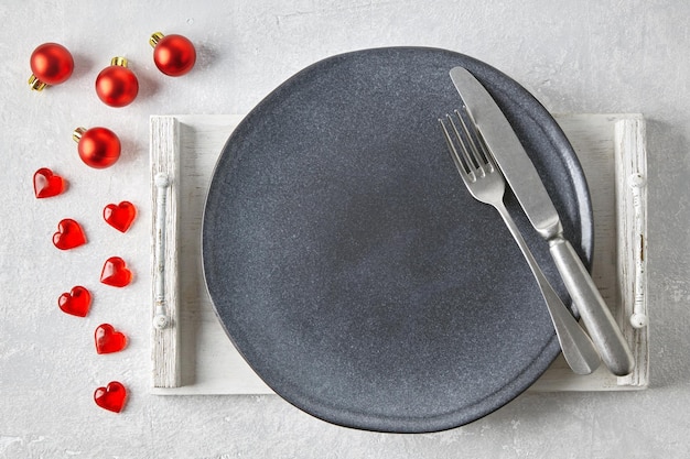 An empty gray ceramic plate with cutlery on a white tray surroun