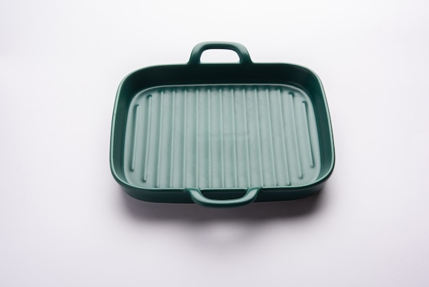 Пустая зеленая керамическая сервировочная миска или форма для выпечки, изолированные на белой или серой поверхности