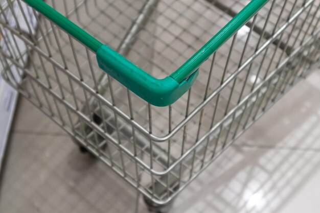 Empty green shopping cart in supermarket aisle