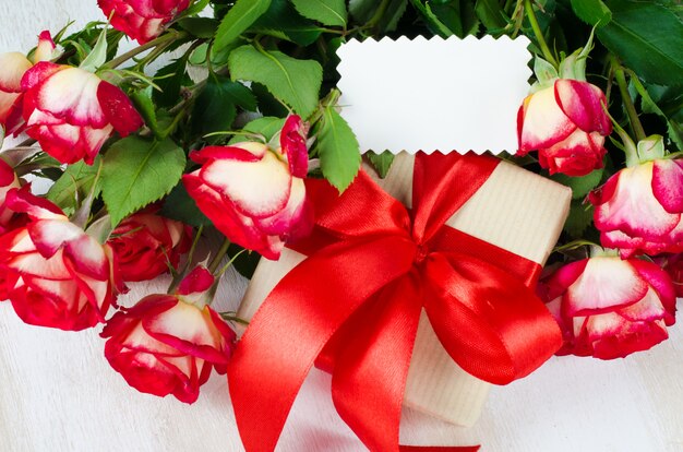 Пустая открытка, красные розы и подарочная коробка