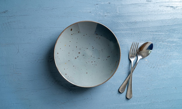 empty grey plate with brown border on blue wooden backdrop top view