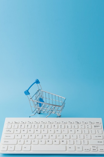 Empty Groceries trolley with keyboard on blue