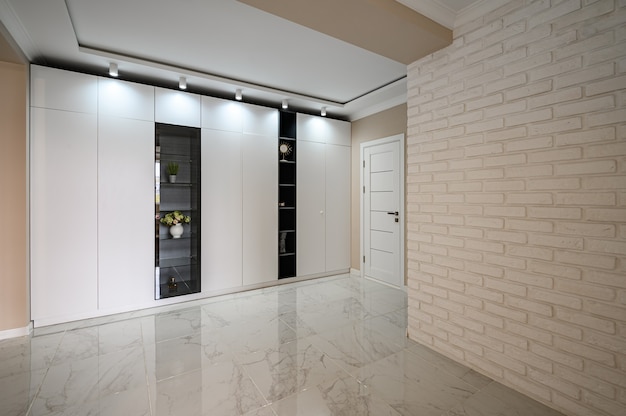 Empty hallway of modern studio apartment with white kitchen and beige bedroom